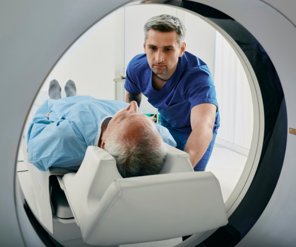 man taking a MRI scan in hospital with the nurse pushing the bed through the machine
